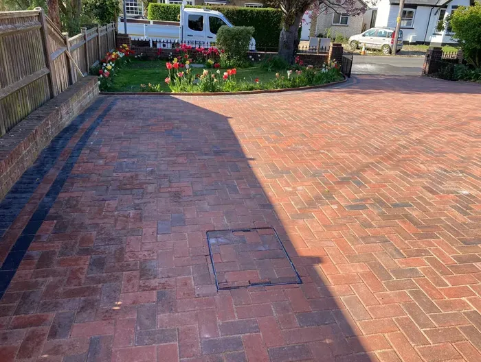 A newly laid block-paved driveway with a herringbone pattern and dark border, leading to a house.