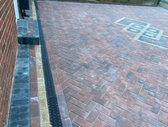 Newly laid multi-coloured block paved driveway with decorative pattern and drainage system.