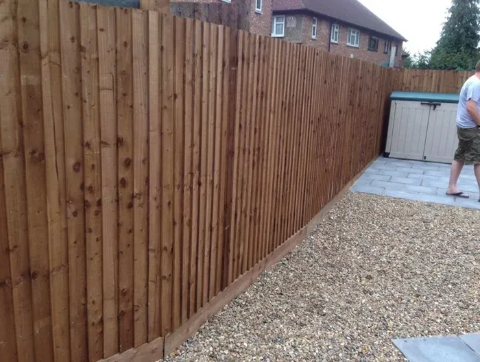 New wooden garden fence installation alongside a gravel path and patio