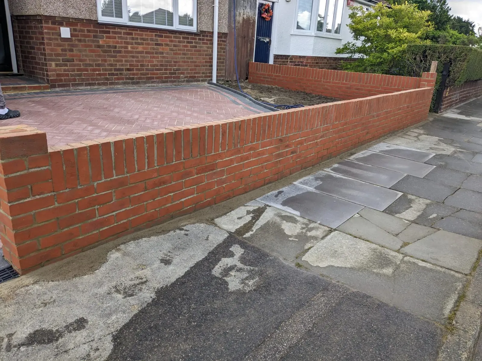 A completed block paving driveway and a new brick garden wall in front of a residential house.