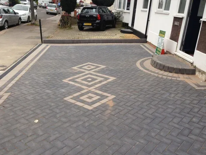 High-quality dark grey block paved driveway with a decorative lighter diamond design, border, and drainage channel.